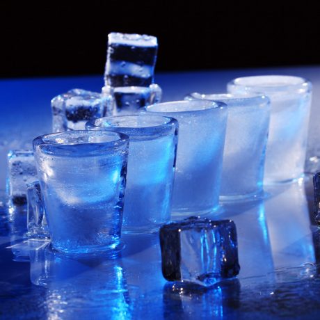 Frozen glasses and ice cubes with cold alcohol drink